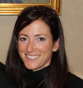 A woman in a black turtleneck smiles for the camera.