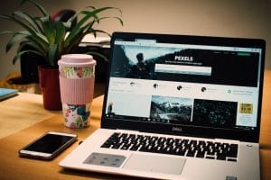 A laptop is sitting on a desk next to a phone and a plant.