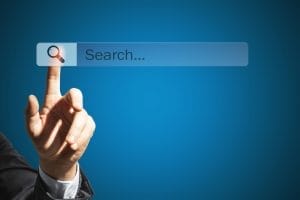 A hand pointing at a virtual search bar with a magnifying glass icon on a blue gradient background, symbolizing Website Design for Local Businesses.